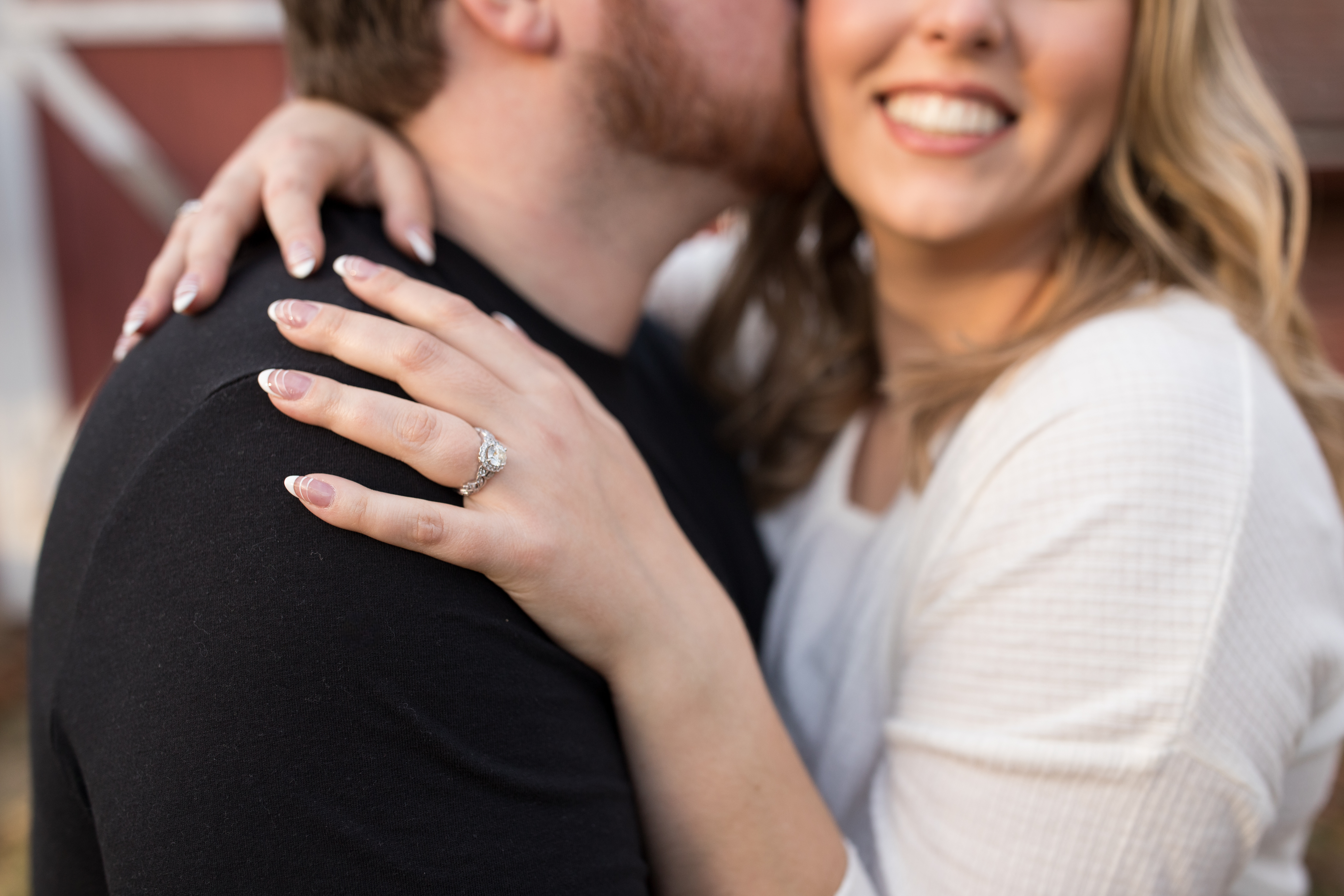 woman resting her hand on fiancé's shoulder to show off engagement ring