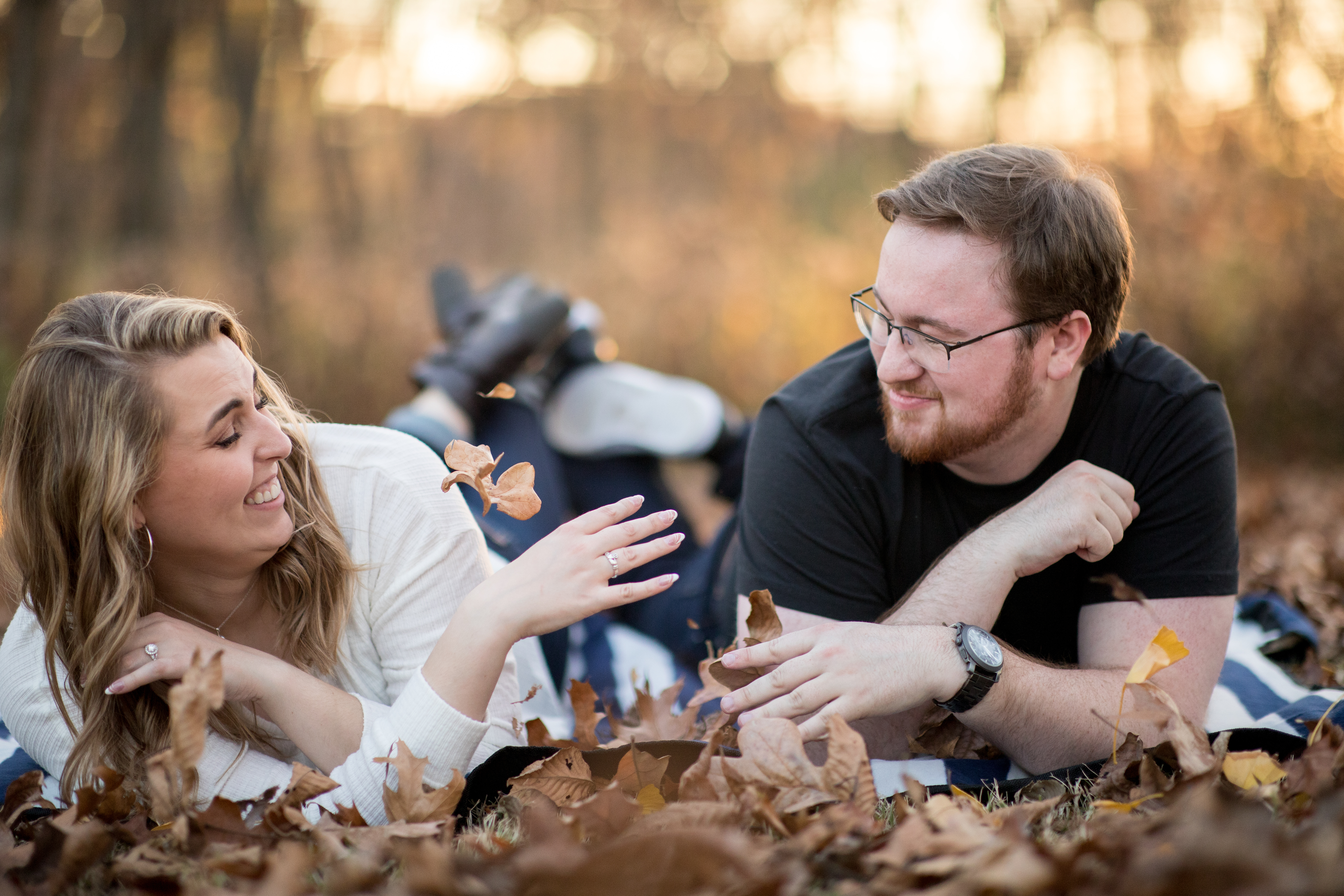 couple laying in fall leaves