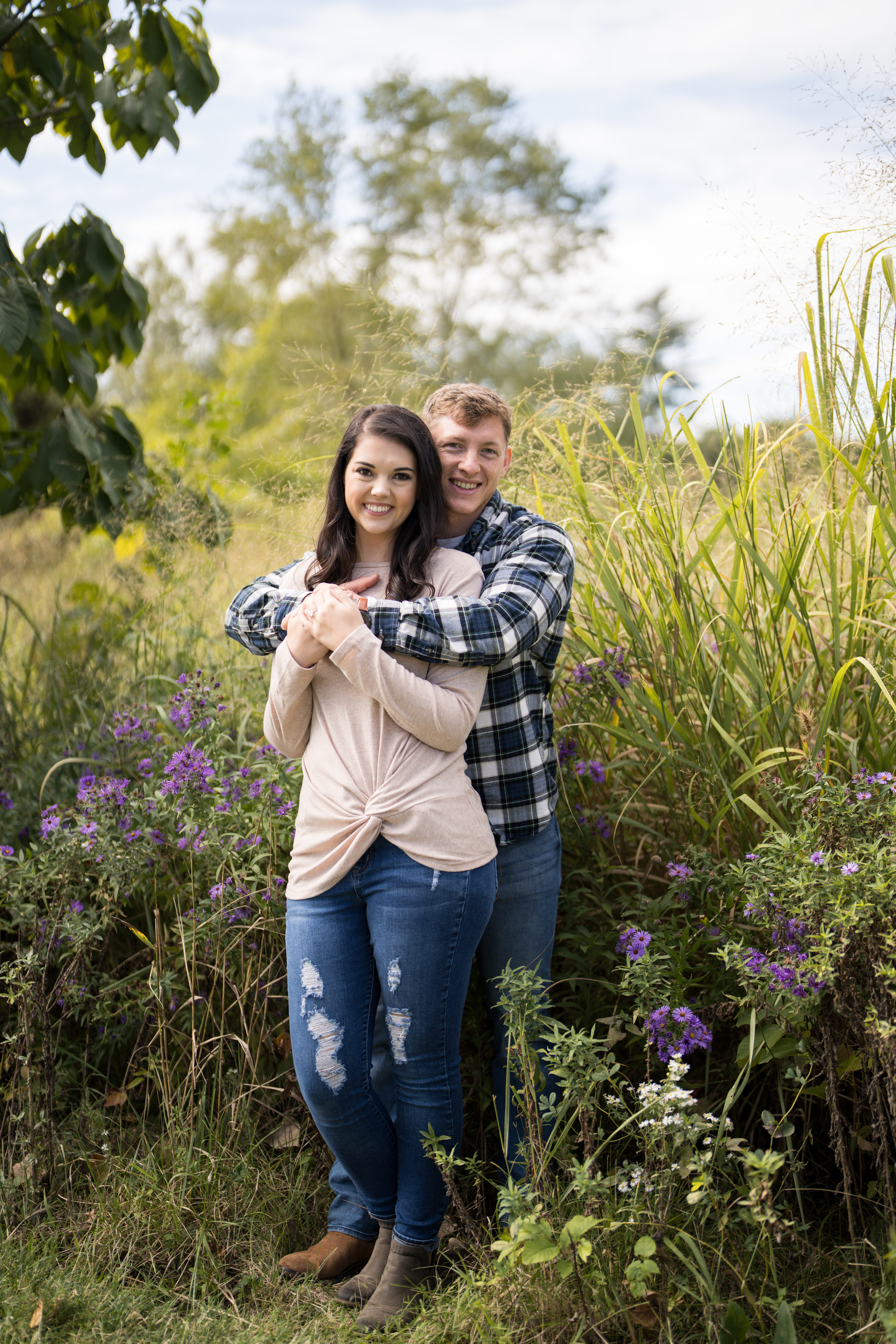 engagement photo of man hugging his fiancé from behind