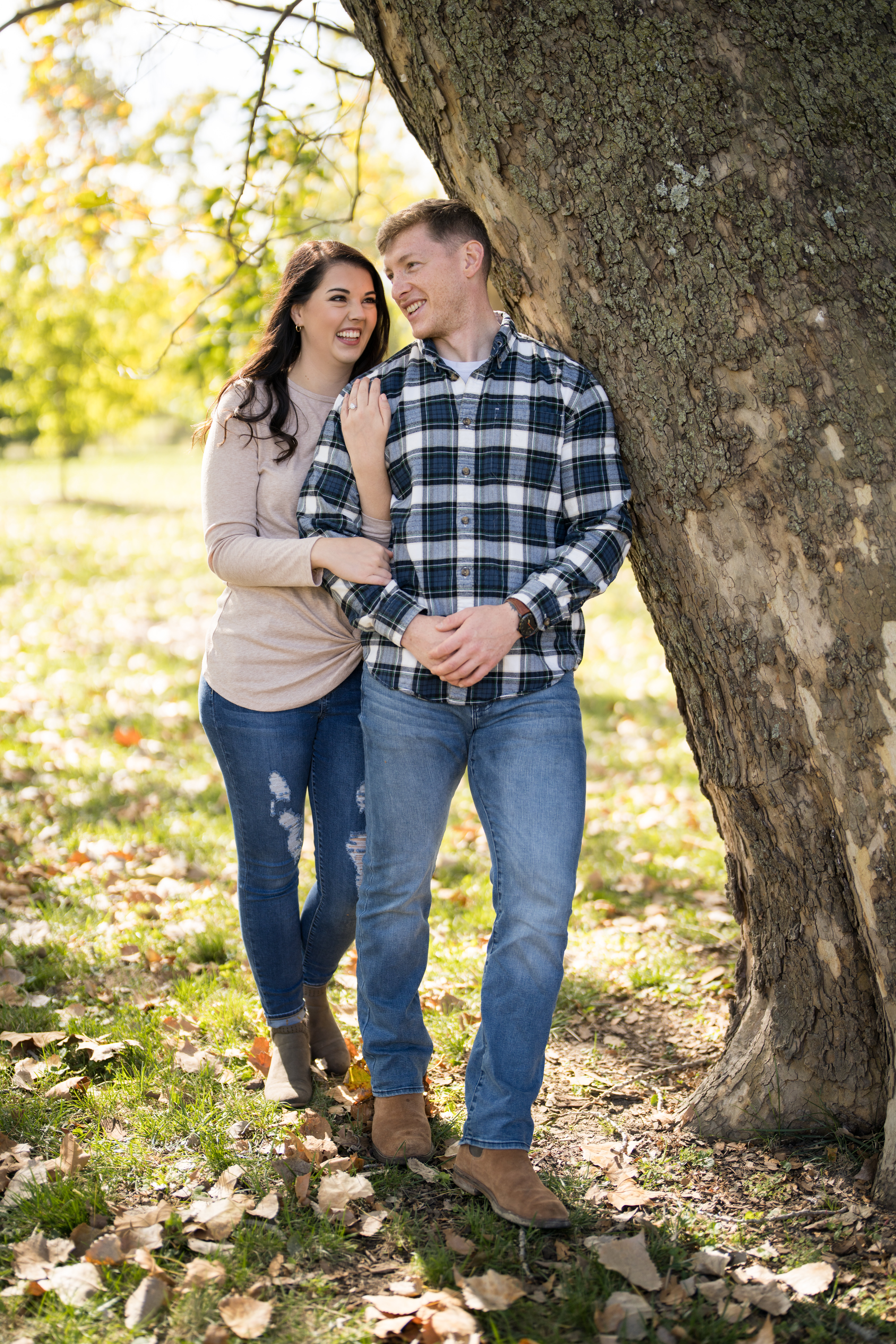 couple smiling and leaning up against a tree