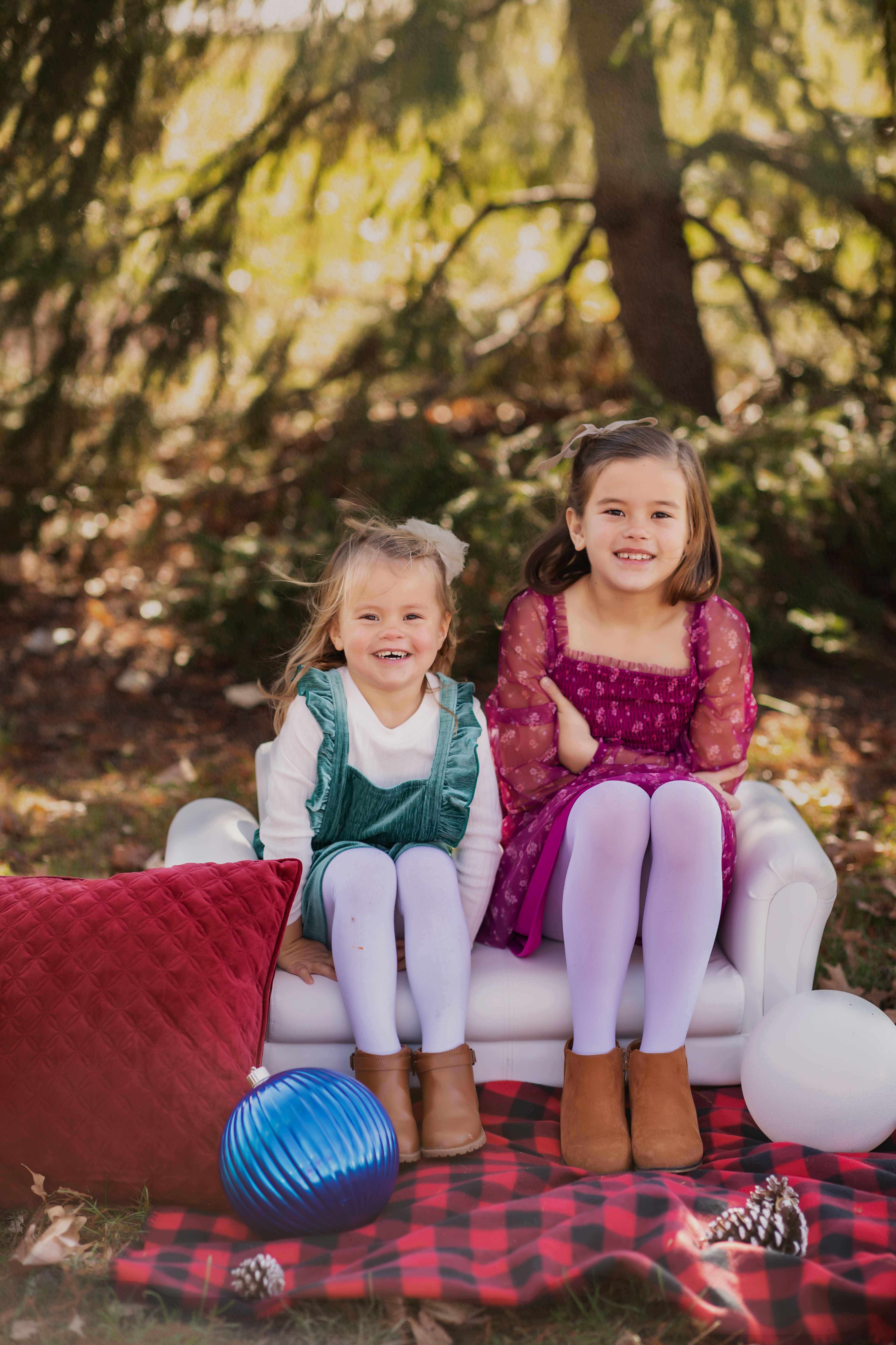 sisters sitting on mini couch with christmas decor photo shoot