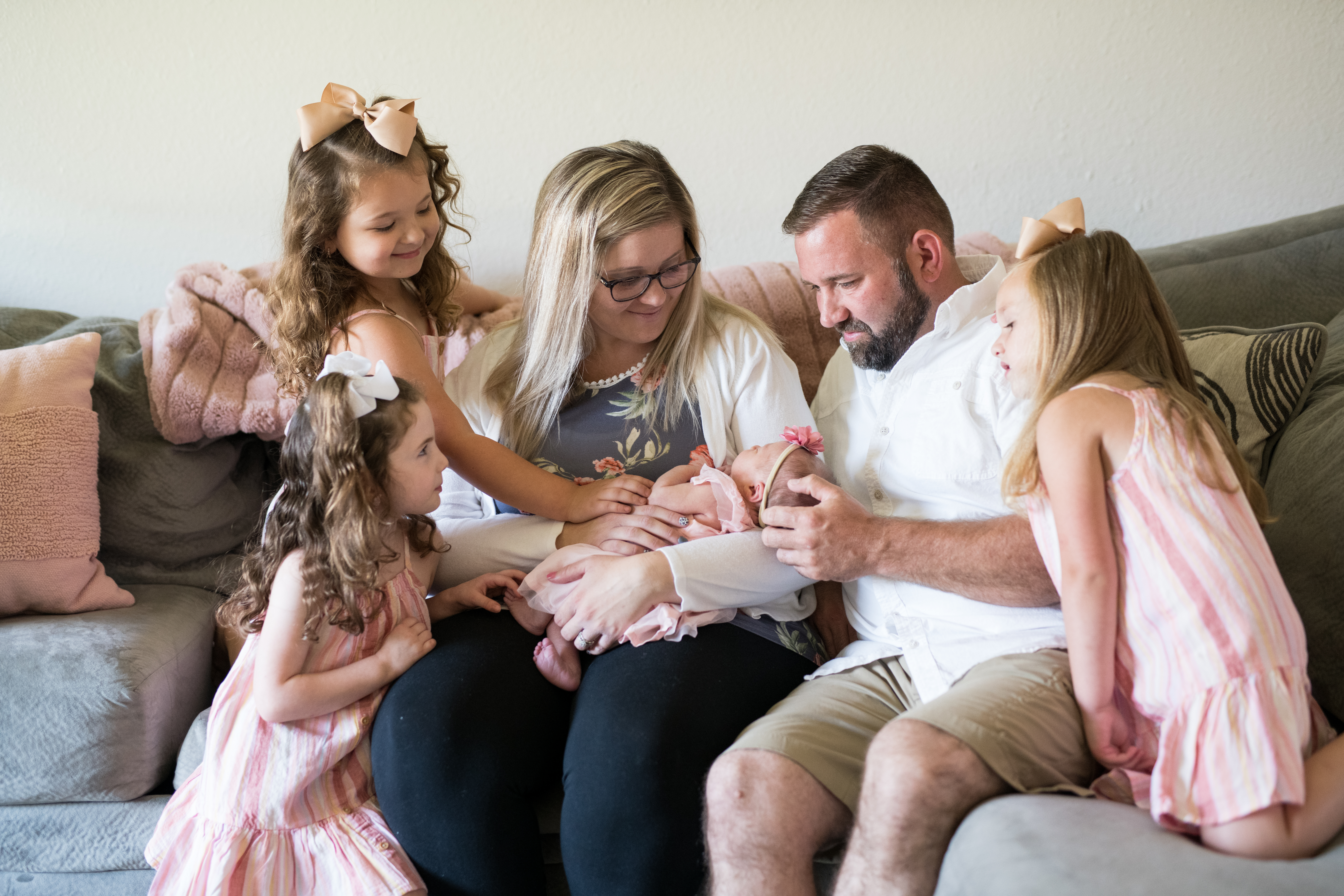 parents sitting on couch with their four daughters