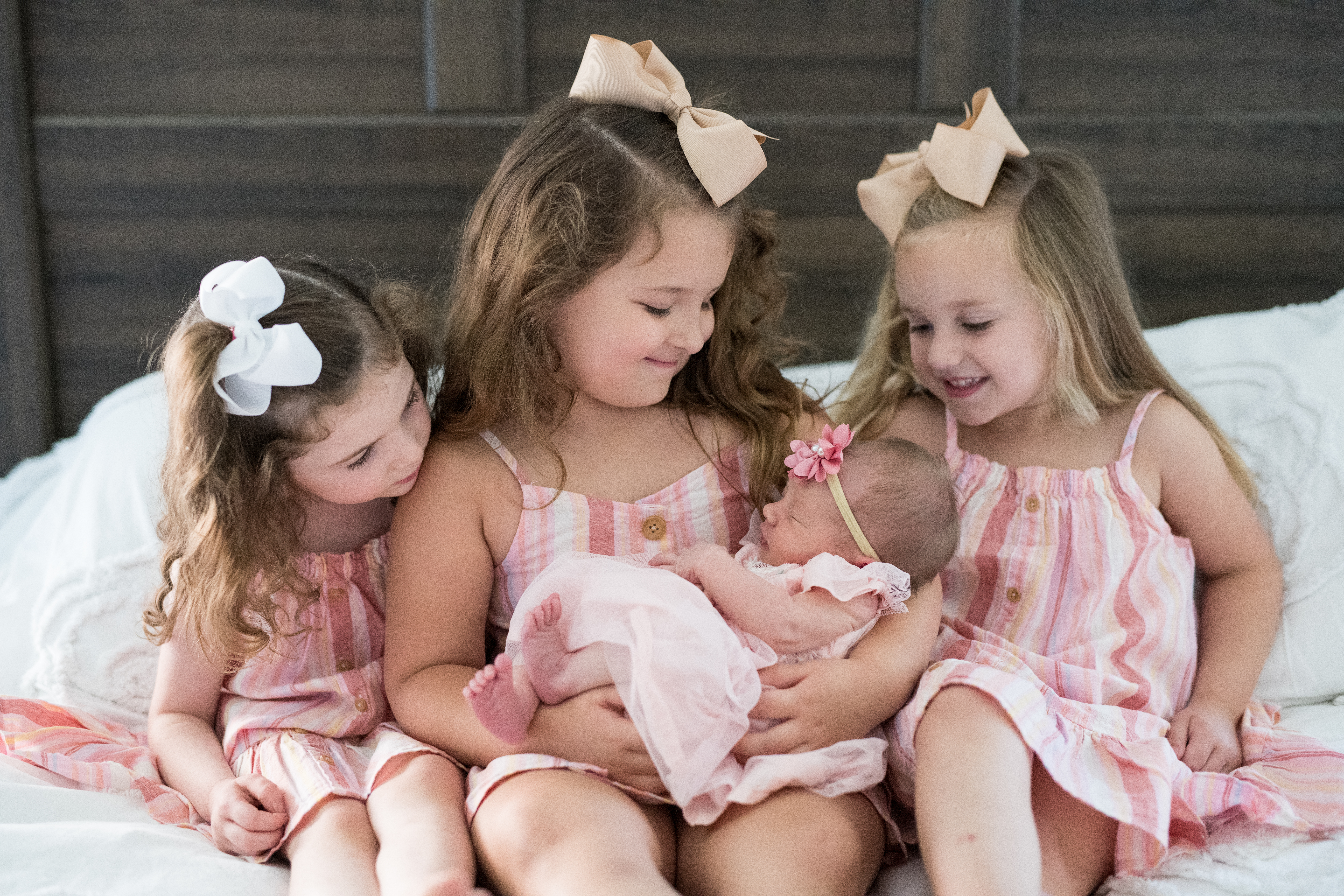 young sisters holding their newborn sister