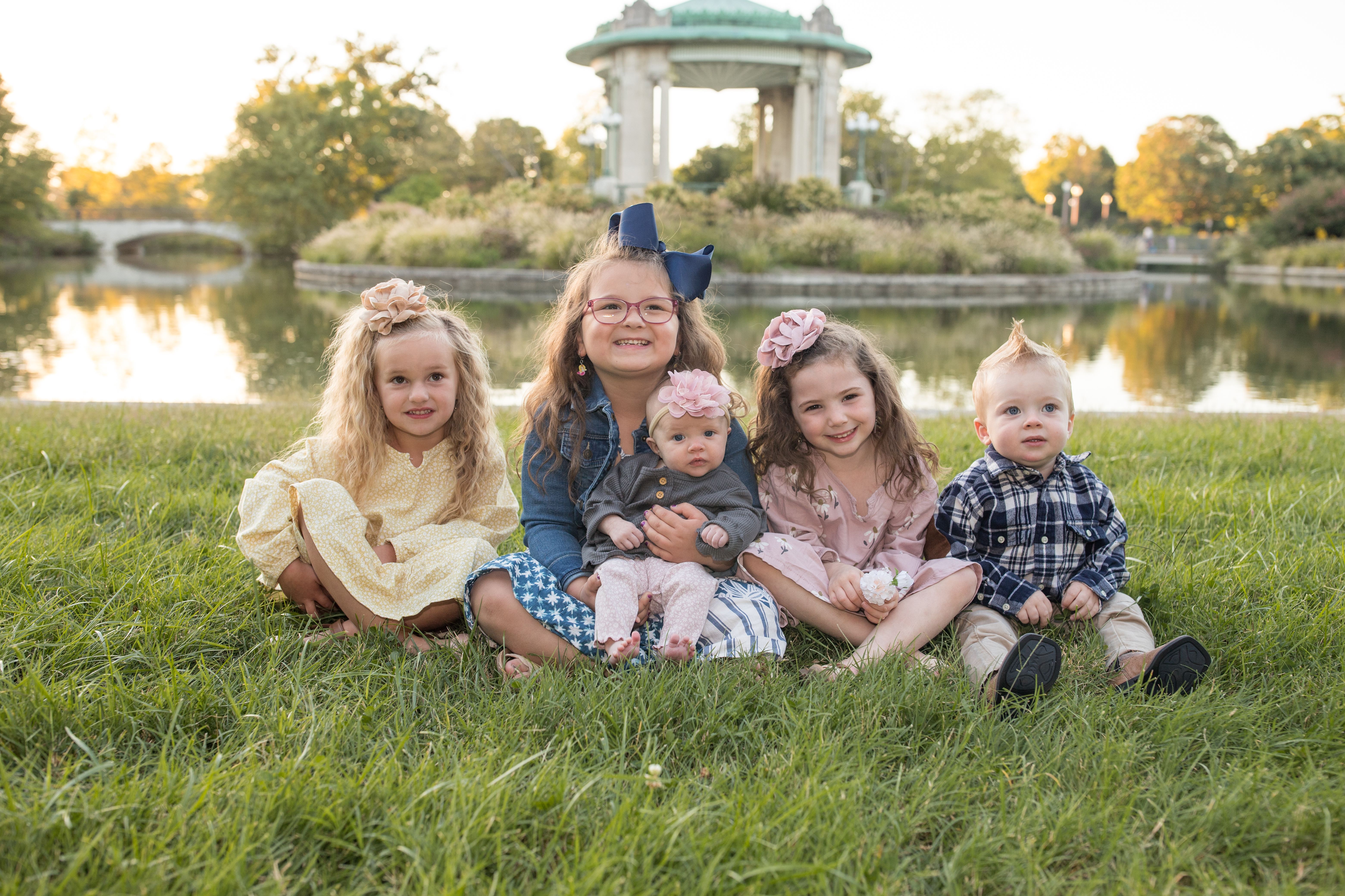 five young siblings posing in the grass next to pond